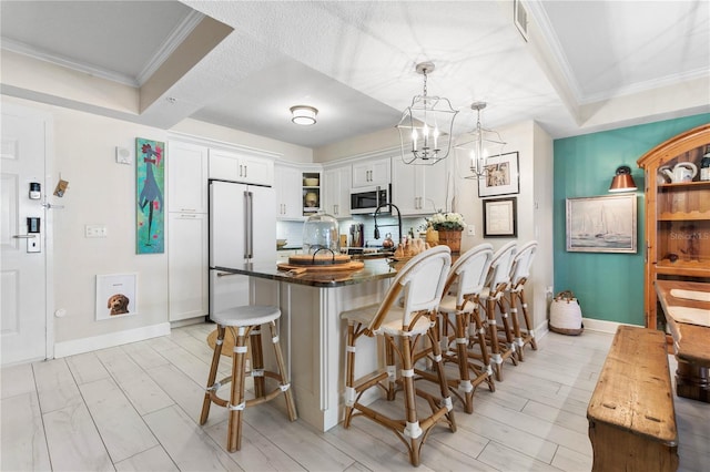 200 Ocean Crest Dr Unit 306, Palm Coast, FL 32137 - kitchen featuring white cabinets, high quality fridge, a breakfast bar, decorative light fixtures, and crown molding