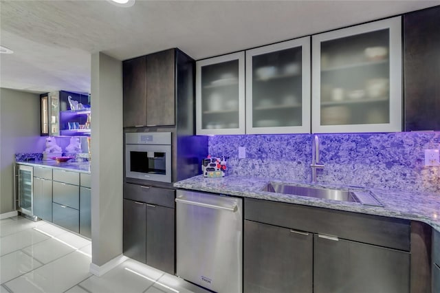 kitchen with beverage cooler, light stone counters, appliances with stainless steel finishes, and glass insert cabinets