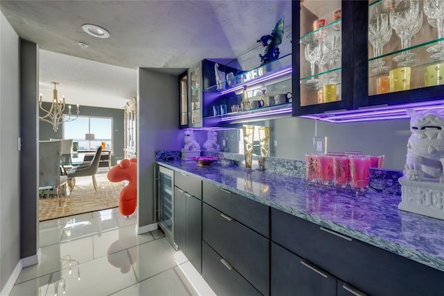 bar with a chandelier, light tile patterned floors, wine cooler, indoor bar, and baseboards