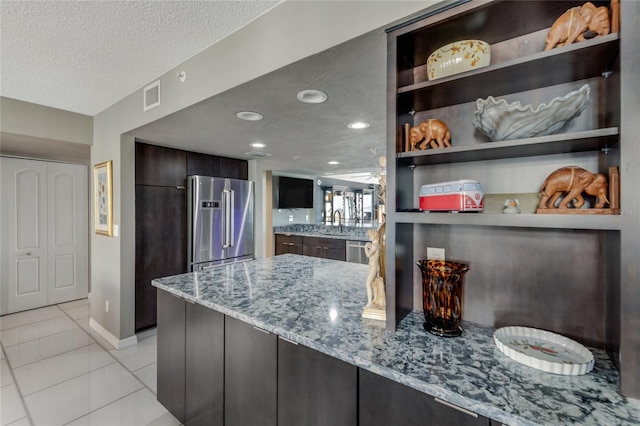 kitchen featuring light stone countertops, stainless steel appliances, a textured ceiling, open shelves, and light tile patterned flooring