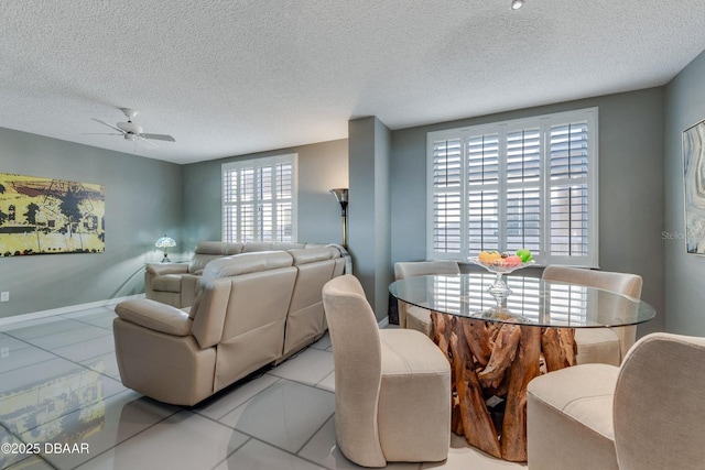 dining room with light tile patterned floors, baseboards, a ceiling fan, and a textured ceiling