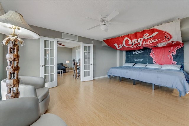 bedroom featuring french doors, visible vents, a textured ceiling, wood finished floors, and baseboards