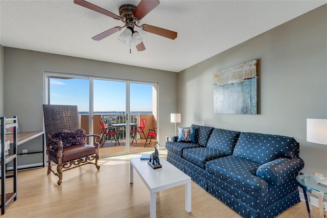 living room with a textured ceiling, light wood-style flooring, and a ceiling fan