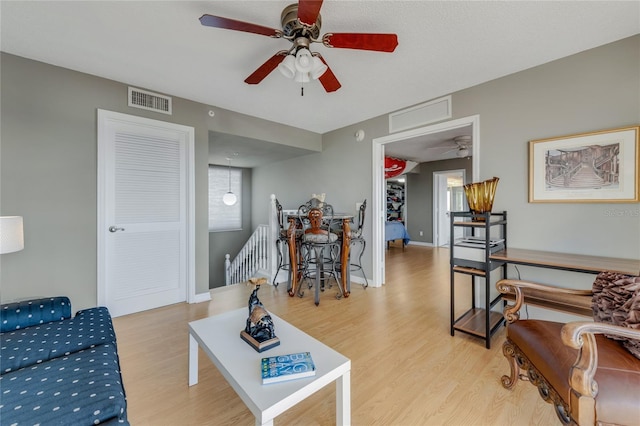 living room featuring light wood-style floors, visible vents, and baseboards