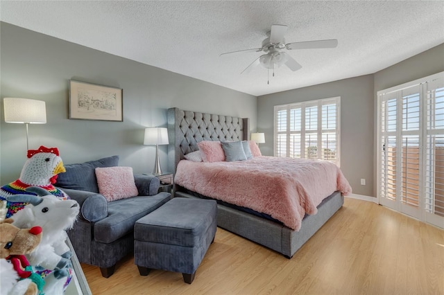 bedroom with light wood-type flooring, baseboards, a ceiling fan, and a textured ceiling