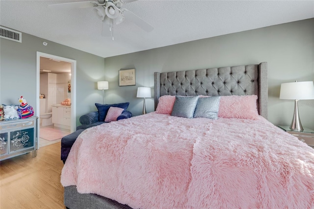 bedroom with light wood-style flooring, connected bathroom, visible vents, and a textured ceiling