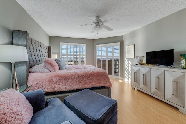 bedroom featuring light wood-style floors, a textured ceiling, baseboards, and a ceiling fan