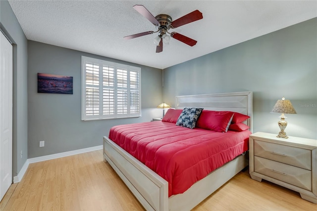 bedroom with ceiling fan, a textured ceiling, baseboards, and wood finished floors