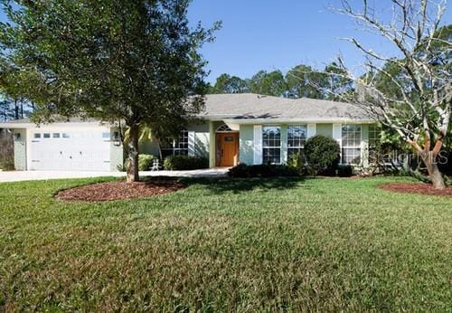 ranch-style home with a front yard, concrete driveway, and an attached garage