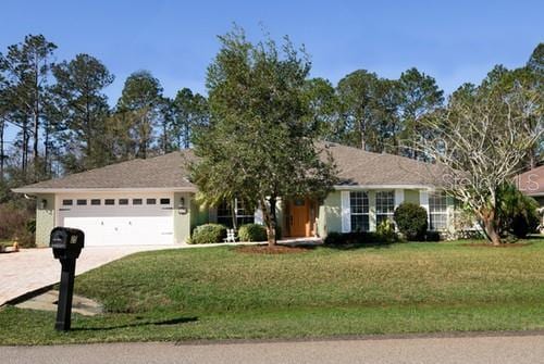 single story home featuring driveway, an attached garage, and a front yard