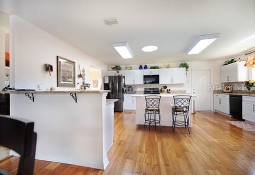 kitchen featuring white cabinets, black appliances, and a breakfast bar