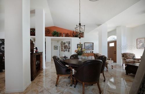 dining space with lofted ceiling, marble finish floor, and a chandelier