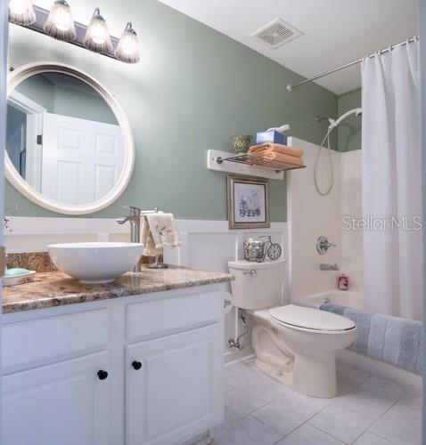 full bathroom with toilet, vanity, visible vents, tile patterned floors, and shower / bathtub combination with curtain