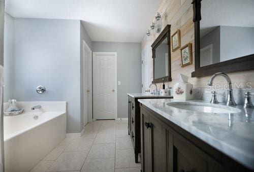 bathroom with tile patterned floors, vanity, baseboards, and a bath