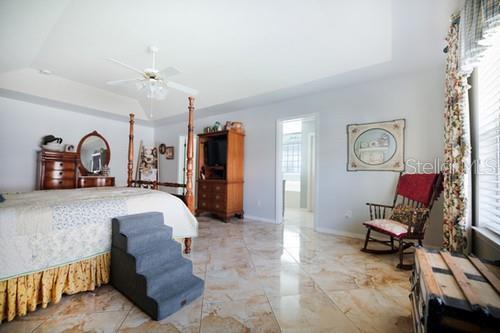 bedroom featuring marble finish floor, multiple windows, baseboards, and a raised ceiling