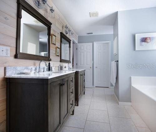 bathroom featuring a garden tub, double vanity, tile patterned flooring, and a sink