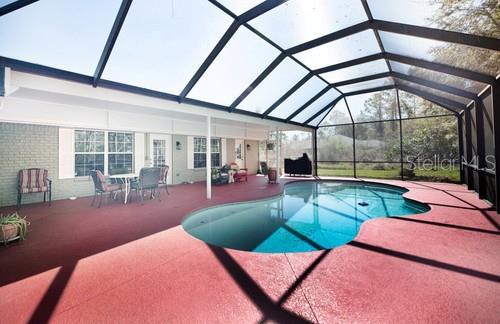 outdoor pool featuring glass enclosure and a patio