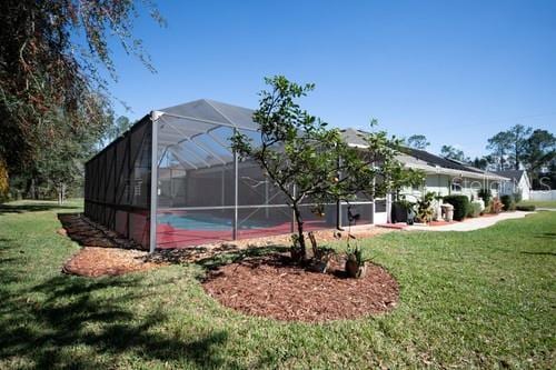 back of house with glass enclosure and a lawn