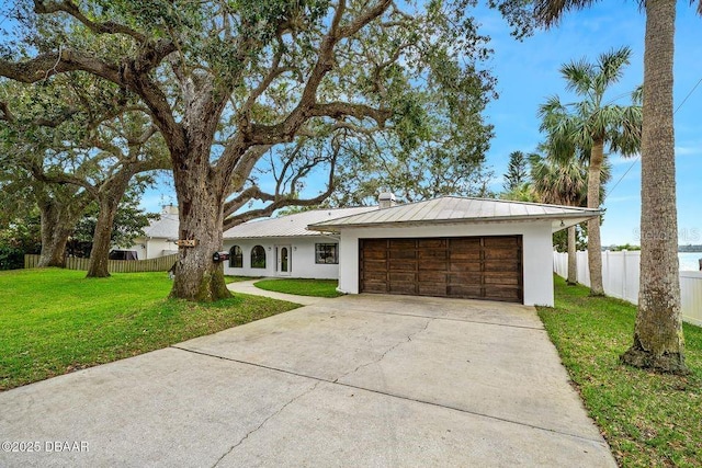 view of front of house featuring concrete driveway, a front yard, fence, metal roof, and a garage