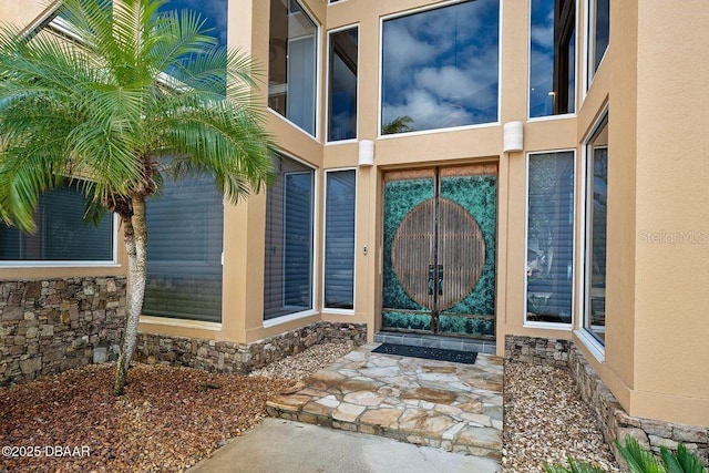 property entrance with stone siding, a gate, and stucco siding