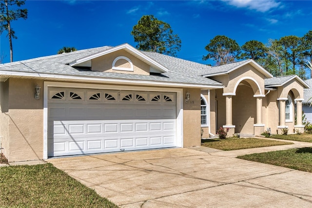 ranch-style home featuring an attached garage, roof with shingles, concrete driveway, and stucco siding