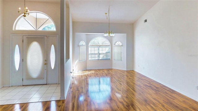 foyer entrance featuring baseboards, light wood finished floors, visible vents, and an inviting chandelier