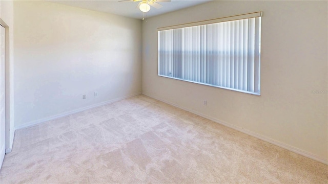 empty room featuring ceiling fan, baseboards, and light colored carpet