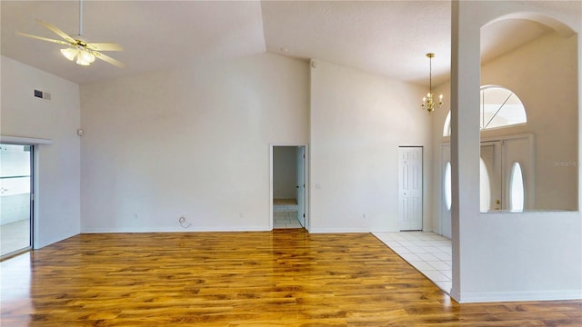 interior space featuring ceiling fan with notable chandelier, high vaulted ceiling, light wood finished floors, and visible vents