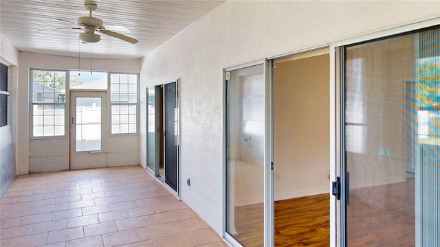 unfurnished sunroom featuring a ceiling fan