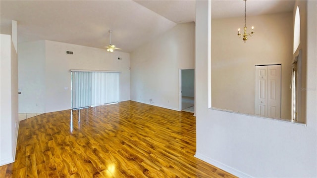 spare room with ceiling fan with notable chandelier, high vaulted ceiling, wood finished floors, and visible vents