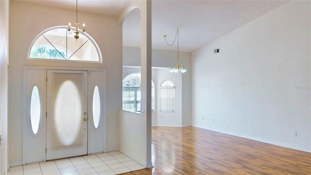 entrance foyer featuring light wood-type flooring, a high ceiling, visible vents, and a notable chandelier