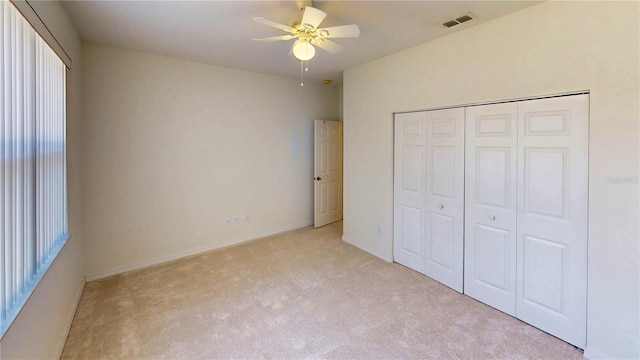 unfurnished bedroom with light carpet, a closet, visible vents, and a ceiling fan