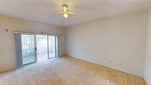 spare room featuring a tray ceiling, a ceiling fan, and light colored carpet