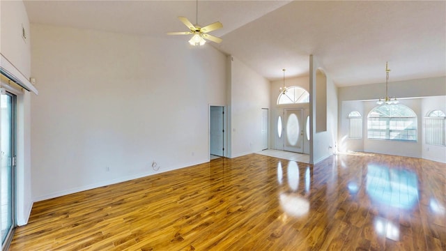 interior space with ceiling fan with notable chandelier, high vaulted ceiling, light wood-type flooring, and baseboards