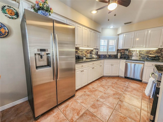 kitchen with decorative backsplash, appliances with stainless steel finishes, light tile patterned flooring, a sink, and white cabinetry