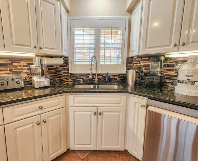 kitchen with tasteful backsplash, stainless steel dishwasher, white cabinetry, a sink, and light tile patterned flooring