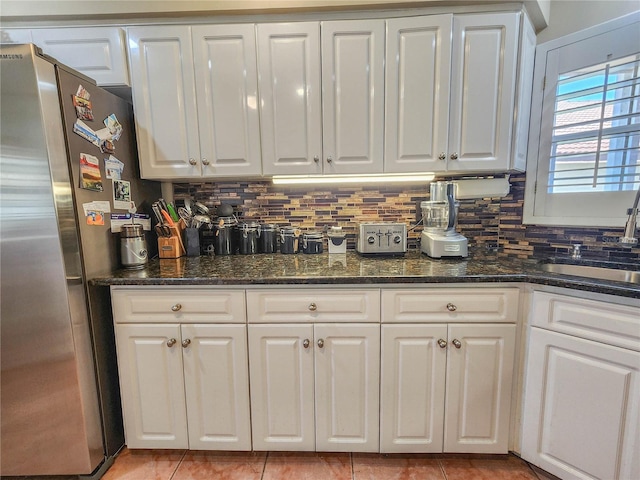 kitchen with a sink, freestanding refrigerator, and white cabinets