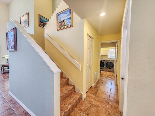 hall with tile patterned floors, independent washer and dryer, baseboards, and stairs