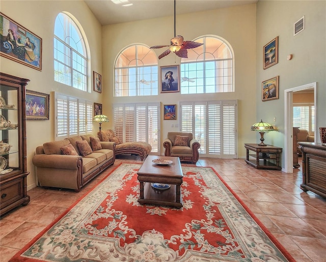 tiled living area featuring a healthy amount of sunlight, visible vents, ceiling fan, and baseboards