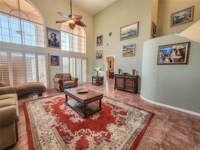 living room featuring ceiling fan, a high ceiling, tile patterned flooring, and baseboards