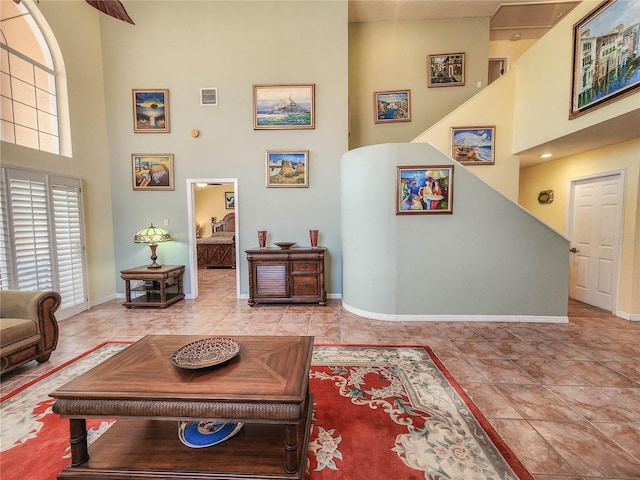 living room with baseboards, a high ceiling, visible vents, and tile patterned flooring