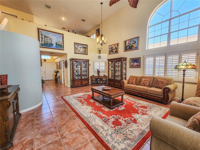 living area featuring baseboards, visible vents, a high ceiling, a notable chandelier, and light tile patterned flooring