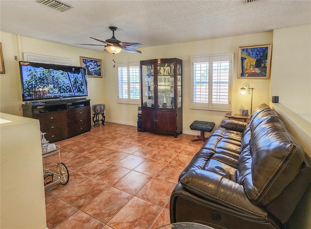 living room with a wealth of natural light, visible vents, a textured ceiling, and light tile patterned floors