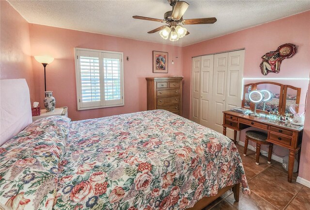 tiled bedroom with a textured ceiling, ceiling fan, and a closet