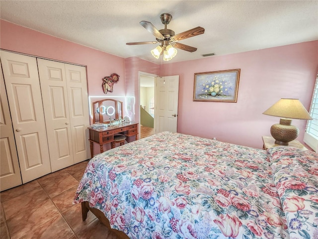 tiled bedroom with a closet, visible vents, ceiling fan, and a textured ceiling