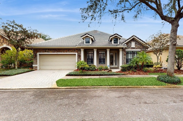 view of front of property featuring decorative driveway, stone siding, and a garage