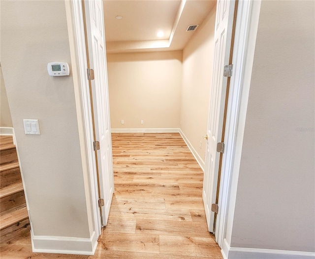 hall featuring light wood finished floors, visible vents, and baseboards