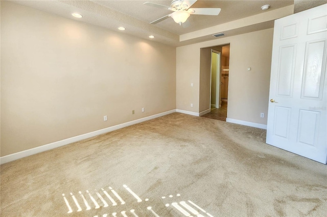 carpeted spare room featuring ceiling fan, recessed lighting, visible vents, baseboards, and a raised ceiling