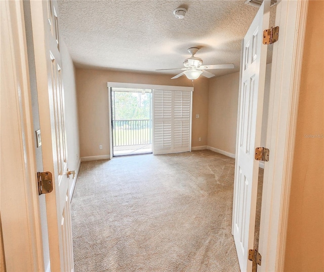 empty room featuring light carpet, a textured ceiling, baseboards, and a ceiling fan