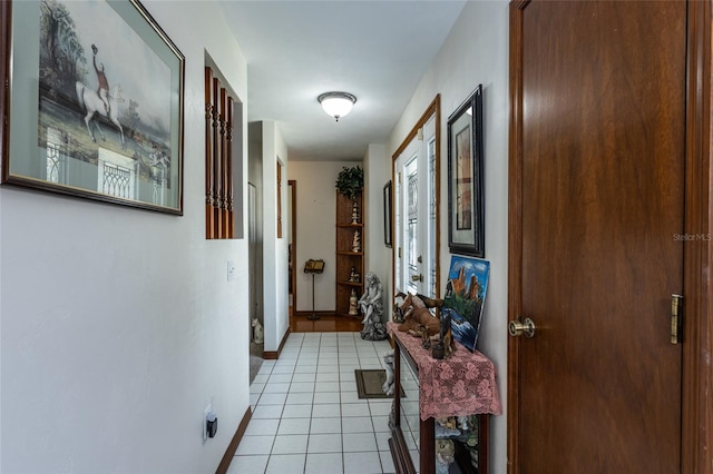 corridor featuring light tile patterned floors and baseboards